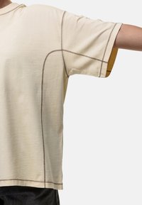 Beige T-shirt met korte mouwen, voorzien van contrasterende bruine stiksels en een relaxte pasvorm, met een subtiele ronde halslijn en een zachte textuur.