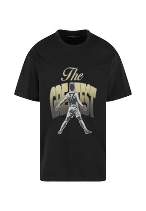 Sort bomulds T-shirt med en grafisk print af en spiller i en hvid uniform, med teksten "The GREATEST" i gyldne bogstaver.