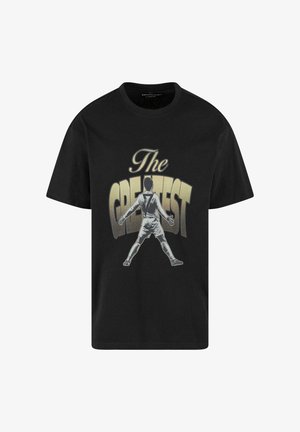 Sort bomulds T-shirt med en grafisk print af en spiller i en hvid uniform, med teksten "The GREATEST" i gyldne bogstaver.