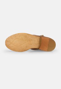 Suela de zapato de cuero marrón con un patrón texturizado, forma curva y un tacón ligeramente elevado. Suela de goma y acabado natural.
