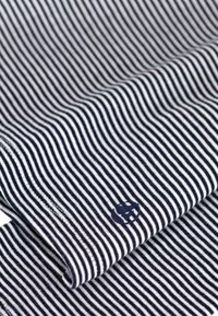 Marine en wit gestreepte stof met een zachte textuur, met een klein rond logo in de onderste hoek.