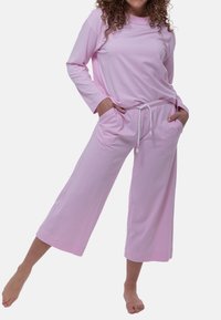 Ljust rosa lounge-set bestående av en långärmad topp och vida byxor med fickor och dragsko i midjan. Mjukt tyg.