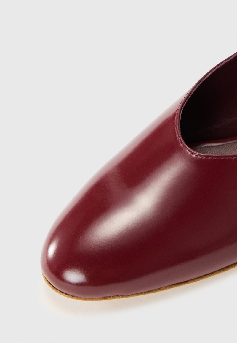 Burgundy leather shoe with a pointed toe and cut-out design. Smooth, glossy finish with a light brown sole. No visible hardware.