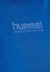 Blauer Stoff in Nahaufnahme mit einem hellblauen "hummel PERFORMANCE"-Logo auf der Oberfläche gedruckt.