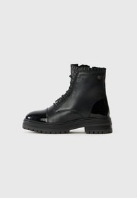 Botas negras hasta medio pantorrilla, hechas de cuero liso y charol, con un borde superior rizado y una suela gruesa texturizada con surcos.