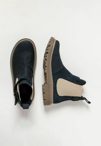 Botas de cuero de charol marinas hasta el tobillo con paneles elásticos laterales y suelas de goma grises. Presenta una banda de tira para facilitar el calzado. Diseño minimalista con detalles prácticos.