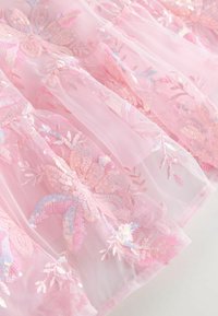 Vaate tulle-kangas, jossa on kukkakirjontaa ja paljetteja, sisältäen pehmeitä tekstuureja ja herkkiä, värikkäitä yksityiskohtia läpi.