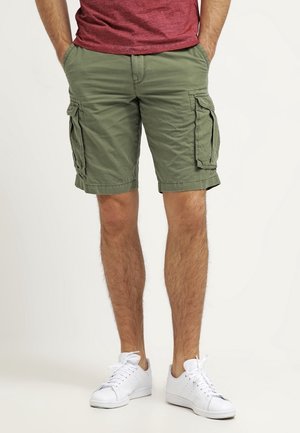 Olivgröna cargoshorts i bomull med två sidofickor med klaff och en avslutning som går precis ovanför knäet, kombinerat med vita sneakers.