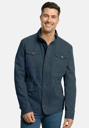 Chaqueta azul marino hecha de una mezcla de algodón, con un cuello alto, dos bolsillos en el pecho y cierres de botón, además de un cordón ajustable en la cintura.