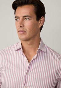 Camicia button-up a righe rosa chiaro e bianca con colletto a punta e texture liscia, caratterizzata da una vestibilità slim e dettagli sulle cuciture laterali.