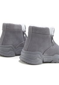 Pelēki potīšu zābaki, kas izgatavoti no gludas zamšādas, ar baltu mākslīgo kažoku iekšpusē, ar sānu rāvējslēdzējiem un teksturētu gumijas zoli, kas nodrošina labāku saķeri.