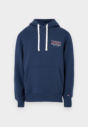 Marineblauwe capuchontrui met witte trekkoorden, voorzak en wit-rood Tommy Hilfiger-logo op de borst en een kleine vlag op de manchet.