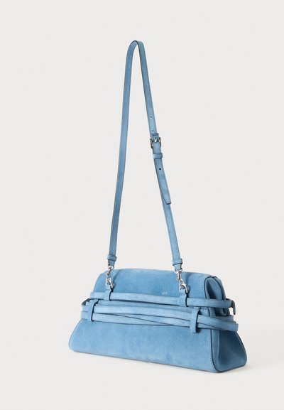 Sac à bandoulière en daim bleu clair avec sangle réglable et doubles bandes horizontales décoratives sur fond uni.