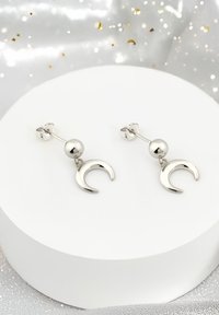 Silverhängande örhängen med rund pärla och halvmåne-design, med en polerad yta och smal postanknytning.