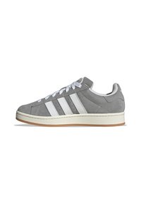 Sneaker in suede grigio con tre strisce bianche, lacci bianchi e suola in gomma. Presenta una punta arrotondata e un collare imbottito.
