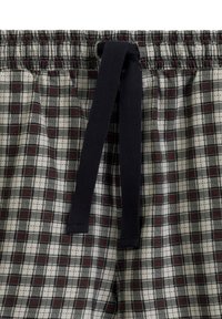 Szorty piżamowe w kratę z granatowym sznurkiem. Materiał ma wzór w siatkę w ciemnoczerwonym, czarnym i białym odcieniu. Elastyczny pas.