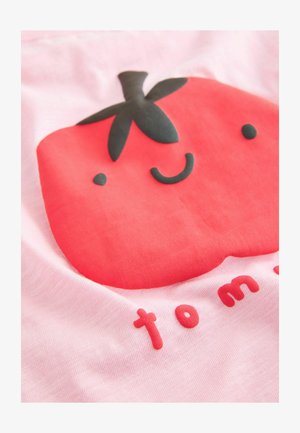 Punane tomati graafika roosal kangal, millel on mustade aktsentidega naeratav nägu. All on sõna "tom" kirjutatud punaste, ümarate tähtedega.