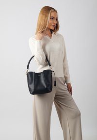 Black leather bucket bag with a structured design, short handle, and gold hardware accents. Smooth texture with a subtle sheen.