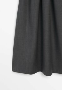 Jupe longueur genou gris foncé avec une texture subtile et de légers plis à la taille, suspendue sur un fond blanc.