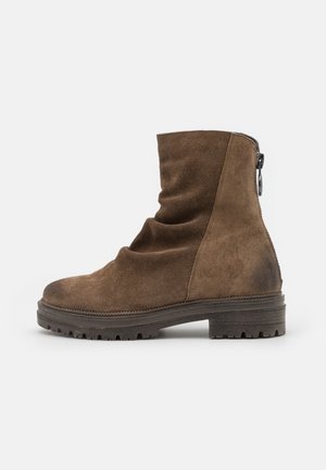 Bottine en daim marron avec bout rond, fermeture éclair latérale, tige souple et semelle extérieure à crampons épaisse pour une meilleure adhérence.