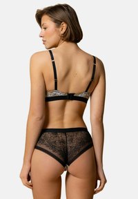 Ensemble de lingerie en dentelle noire comprenant un soutien-gorge à motif avec des bretelles réglables et une culotte taille haute assortie avec des détails floraux.