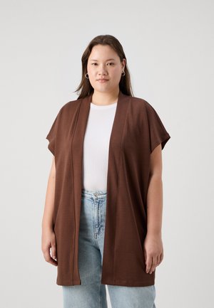 Brun åben-front kimono-stil cardigan lavet af blødt stof, med korte ærmer og en afslappet pasform, båret over en hvid toppen og blå jeans.