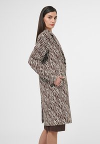 Wollen mantelmix met een abstract patroon in bruin en crème, lange mouwen, een reverskraag en zijzakken. Halflang ontwerp.