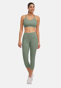 Set atletico verde composto da un reggiseno e leggings capri a vita alta. Realizzato in tessuto liscio ed elasticizzato. Design minimalista con un branding sottile.