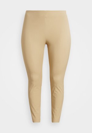 Leggings beige hechos de una tela elástica y suave con un diseño ajustado, que se estrecha en el tobillo, sin costuras visibles ni detalles de hardware.