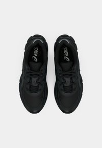 Fekete sportcipők mintás felsőrésszel, lekerekített kialakítással és fűzővel elöl, valamint diszkrét logóval a nyelvén.