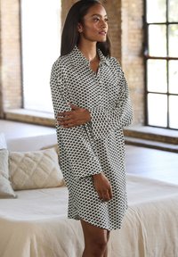 Juoda ir balta geometrinio rašto ilgomis rankovėmis, su sagomis, sukrenta su apykakle ir laisvu siluetu, pagaminta iš lengvos medžiagos.