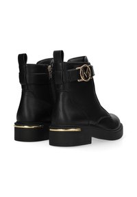 Las botas de tobillo de cuero negro cuentan con una cremallera lateral, un acento de logo en tono dorado en la correa y un tacón grueso con una banda dorada.