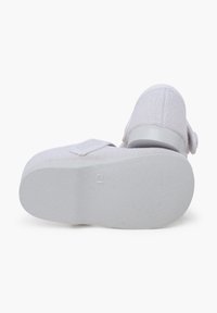 Pantofii din textil alb au un superior din plasă texturată, curea ajustabilă și o talpă din cauciuc alb solid, cu un tocuri ușor.