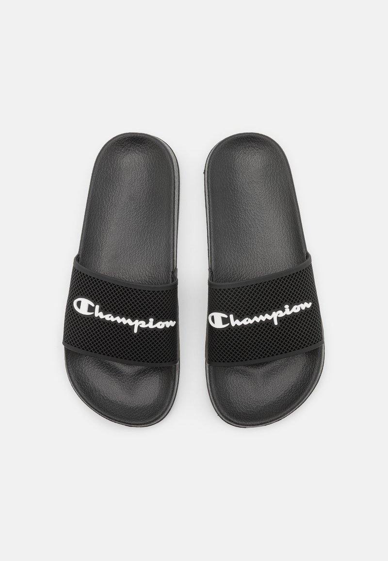 Schwarze Rutsch-Sandalen mit strukturierter Oberseite und Netzriemen, die das weiße "Champion"-Branding tragen. Glatte Sohle und abgerundetes Design.