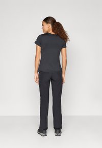 Camisa preta de manga curta combinada com calças pretas, exibindo um design simples e um acabamento texturizado. Calçado casual completa o conjunto.