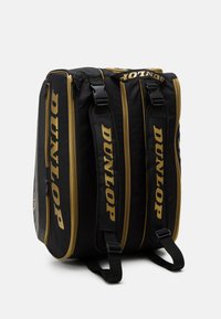 Zaino nero con accenti dorati, realizzato in un tessuto resistente, dotato di tre compartimenti e cerniere visibili. Logo "DUNLOP" ben in evidenza.