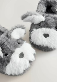 Pantofole grigie pelose a forma di coniglio con dettagli bianchi, caratterizzate da un volto cucito, orecchie pelose e una texture morbida.