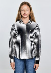 Camicia a righe in blu navy e crema, con colletto a punta, maniche lunghe e taschino sul petto. Realizzata in tessuto leggero.