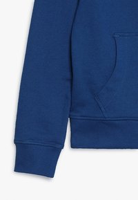 Felpa blu con una texture morbida, polsini a coste e una tasca a marsupio sul davanti. Il design è semplice e dallo stile casual.