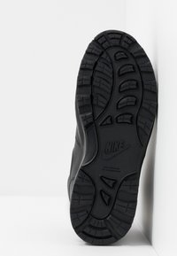 Sneaker Nike nera con suola in gomma testurizzata, caratterizzata da scanalature profonde e dettagli del logo. Le aree del tallone e della punta della scarpa sono rinforzate per una maggiore durata.