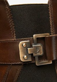 Primo piano di una cintura in pelle marrone con fibbia rettangolare in ottone e un pannello in tessuto nero texturizzato sottostante.