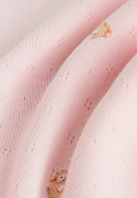 Rosa stickat tyg med en ribbad textur, med små, broderade ankor. Tyget har ett mjukt och mysigt utseende.