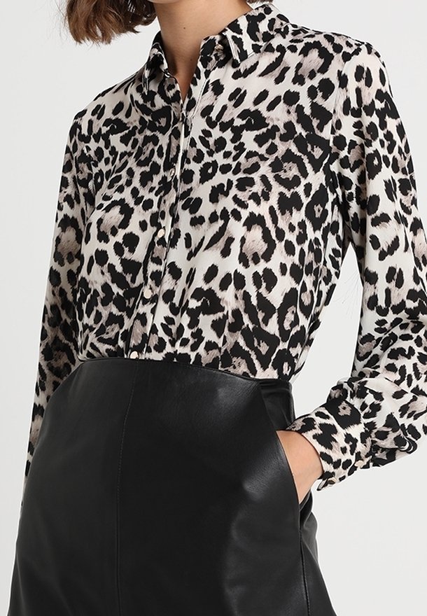 Leopard print blouse in lightweight fabric with a classic collar, long sleeves, and a button front, paired with a high-waisted leather skirt.