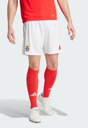 Pantaloni corti bianchi da calcio con logo del Benfica e tre stelle dorate, abbinati a calze rosse al ginocchio con strisce bianche Adidas e scarpe bianche.