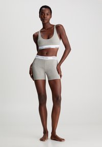 Grå bomull sports-bh og shorts sett med elastisk hvit midjebånd med 'Calvin Klein' logo. Enkel design, slim fit og sømløs tekstur.