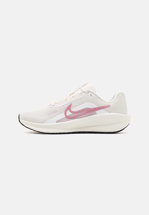 Lettvekts løpesko i hvitt mesh med rosa detaljer, snøring og en teksturert såle. Har en polstret mellomsåle og buet tådesign.