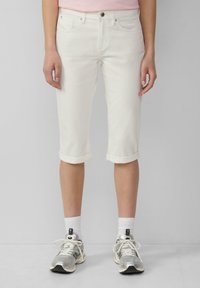 Shorts en denim blancs à mi-cuisse avec des revers. Pr�ésente un design classique à cinq poches et des coutures contrastées. Assortis avec des baskets grises.