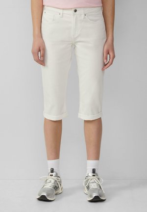 Weiße, knielange Jeansshorts mit umgeschlagenen Säumen. Verfügt über ein klassisches Fünf-Taschen-Design und kontrastierende Nähte. Kombiniert mit grauen Sneakers.