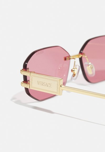 Ochelari de soare octogonali cu lentile roz, detalii din metal aurit și un accent decorativ lateral cu logo-ul "Versace".
