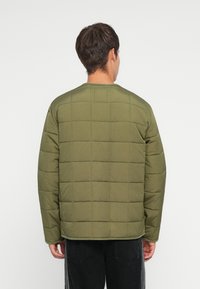 Olive spalvos pūkinė striukė su siuvinėta struktūra, apvaliu kaklu ir ilgomis rankovėmis, pagaminta iš lygios medžiagos, matoma iš nugaros.